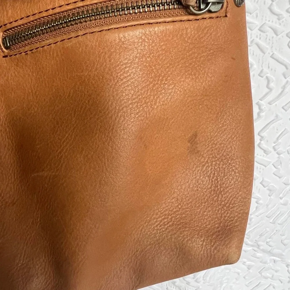 Tan leather shoulder bag with zipper closure, multiple pockets & braided tassel